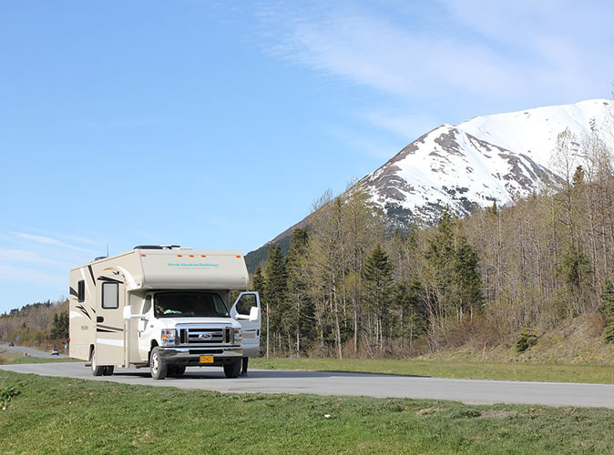 a campervan on a road with a mountain in the background