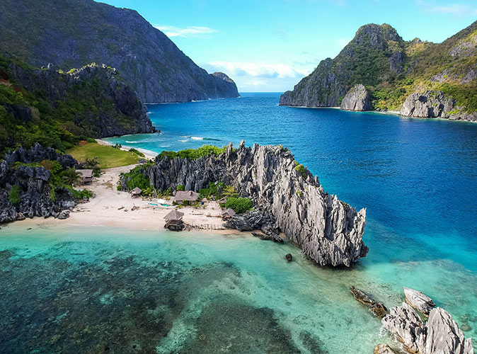 a sandy beach and rock formations in a large body of water