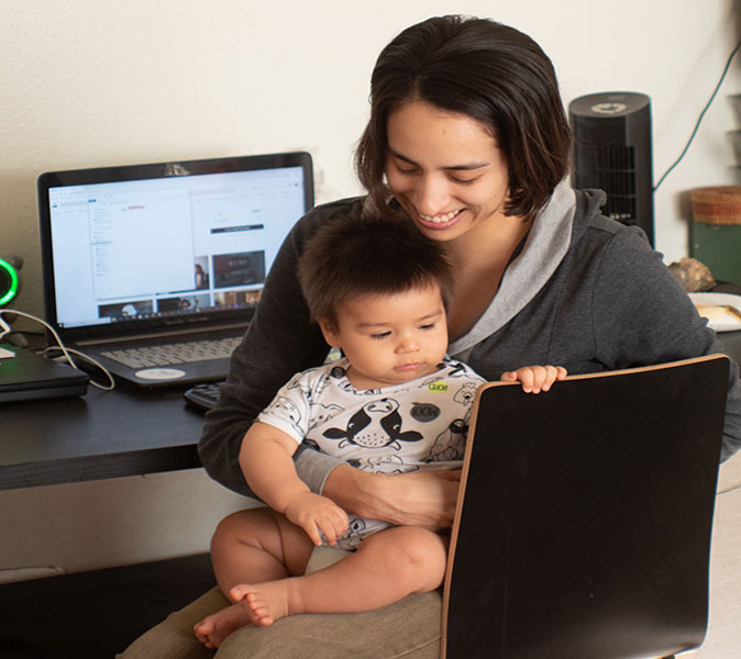A woman with a child on her lap and a laptop in front of her