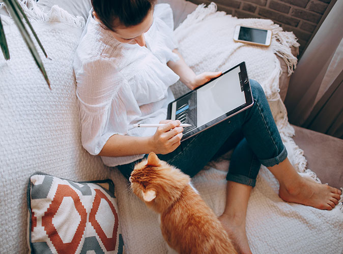 A woman cat sitting as a digital nomad job A woman working on her tablet with a cat next to her