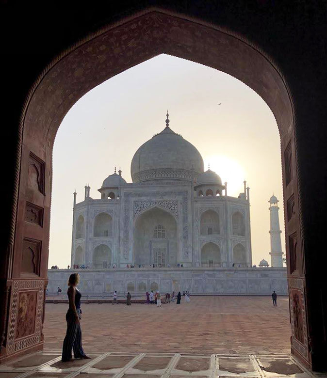 silhouette of a woman sthanding in a large door frame looking at an immense mausoleum of white marble