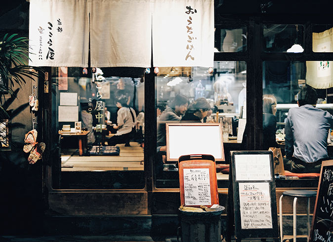 a Japanese restaurant photographed from the outside with several people sitting inside