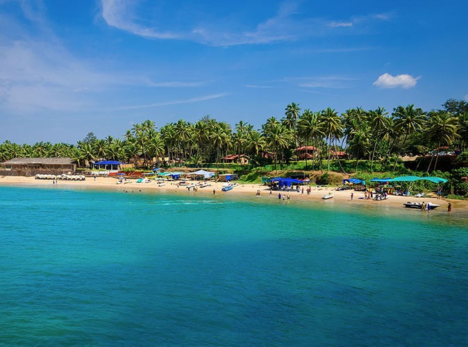 a beach with several people, jet skis and palm trees