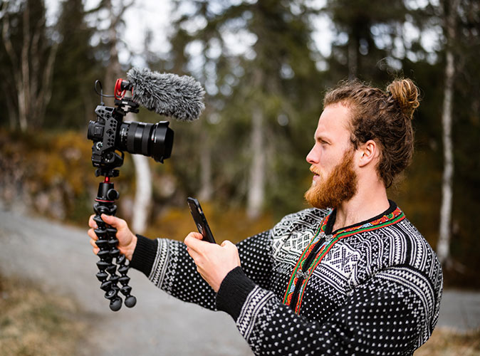 Vlogging as a digital nomad job A man holding his phone and a camera to create his vlog