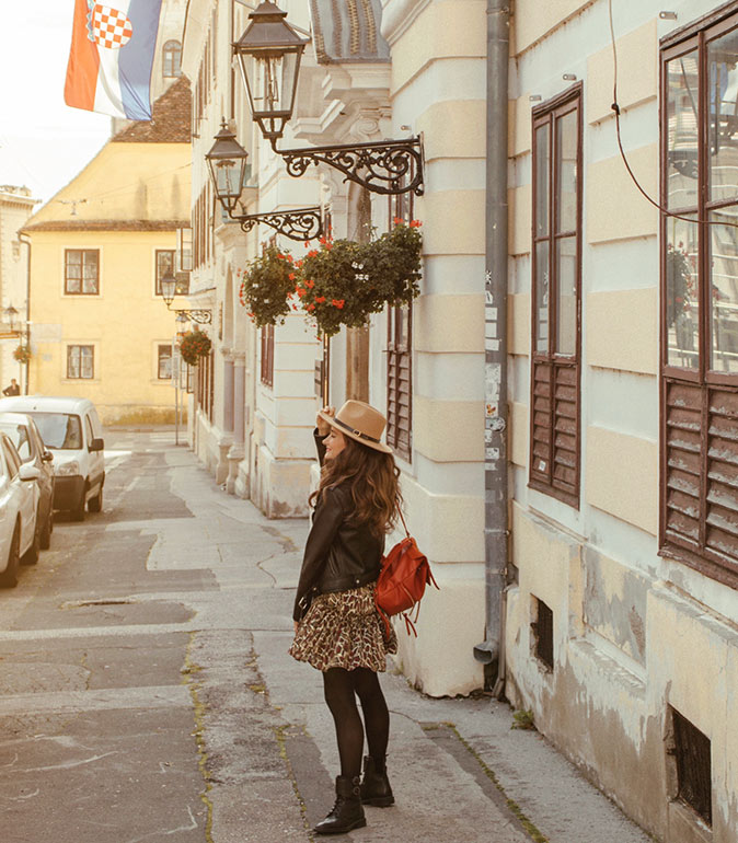 A woman with a brown hat smiling, on a street in Zagreb