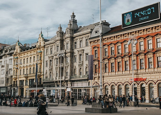several people walking on a street in front of beautiful historic buildings