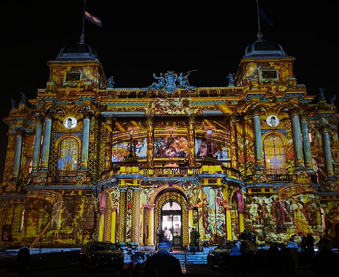 the exterior of a historic building light up with different colors and images