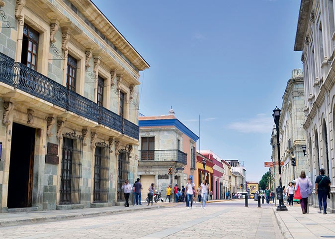 Is Oaxaca safe? A wide street with several people, lined with typical Mexican buildings