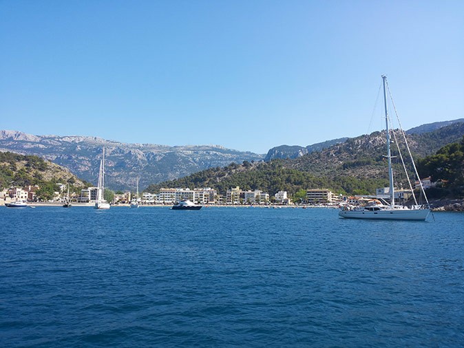 A romantic sailing getaway to Mallorca, Spain A wide bay with several boats and mountains in the background