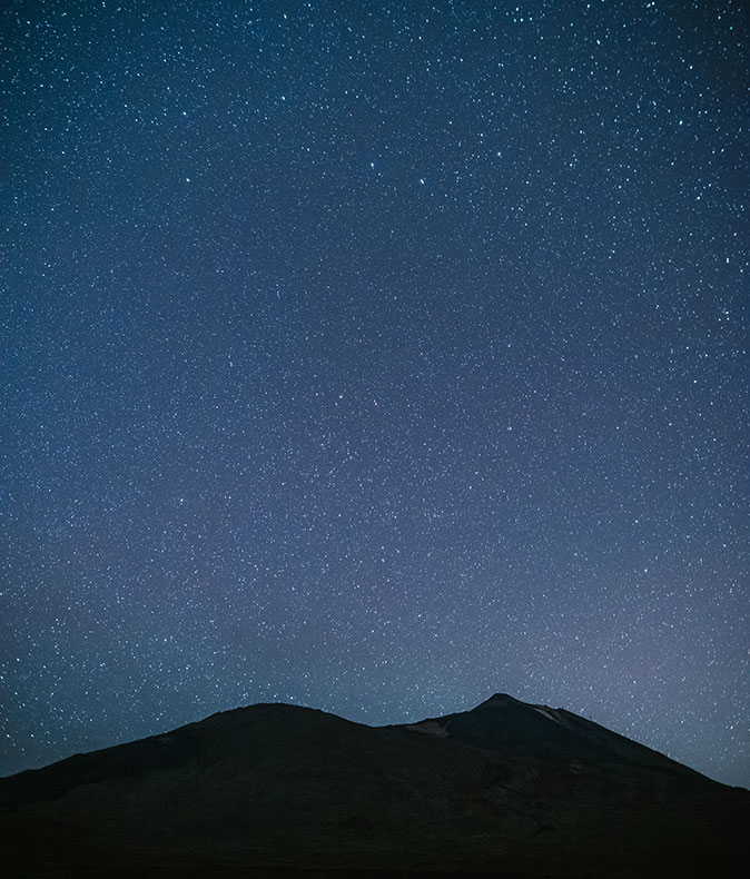 Stargazing, a romantic thing to do in Tenerife silhouette of a mountain with a dark blue sky filled with stars