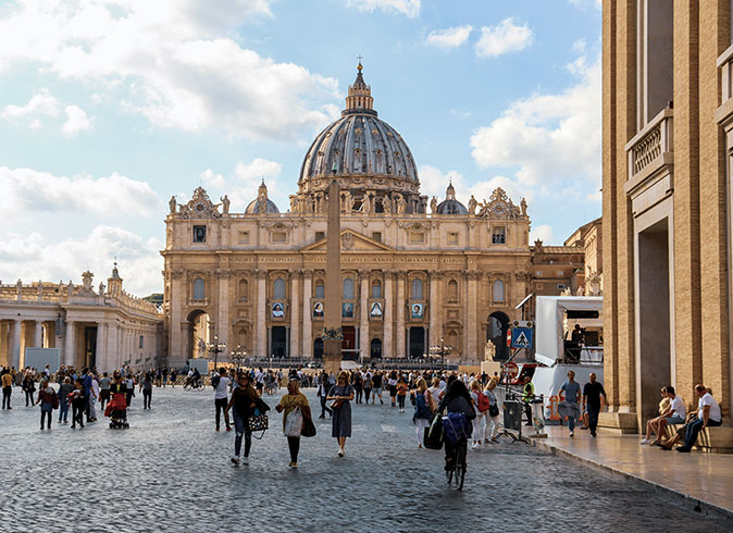 people walking on a large square with a brown church in the background