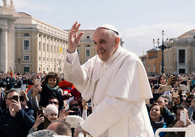 Seeing the Pope while visiting Vatican City Pope Francis waving at the Vatican, surrounded by a lot of people