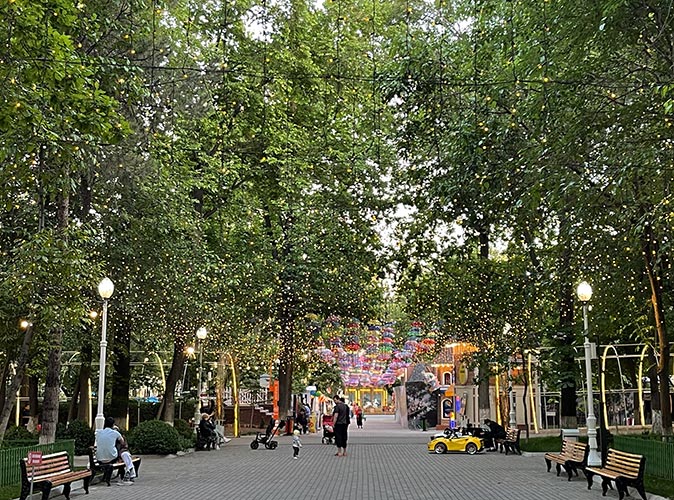 A park in Tashkent A park in Tashkent with large green trees and several people walking on a paved path