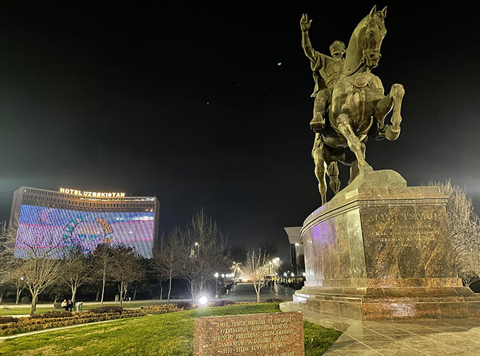 the weather in Uzbekistan A statue of a man on a horse with a high rise building in the background