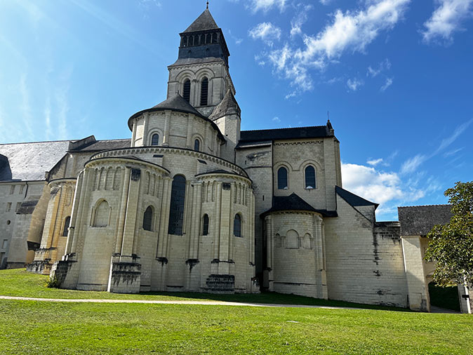 A large, light brown abbey with green grass in front of it
