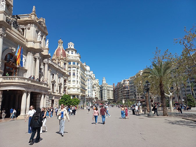 Eco-friendly things to do in Valencia: walk around the city center A large city square with many pedestrians, trees, and historic buildings