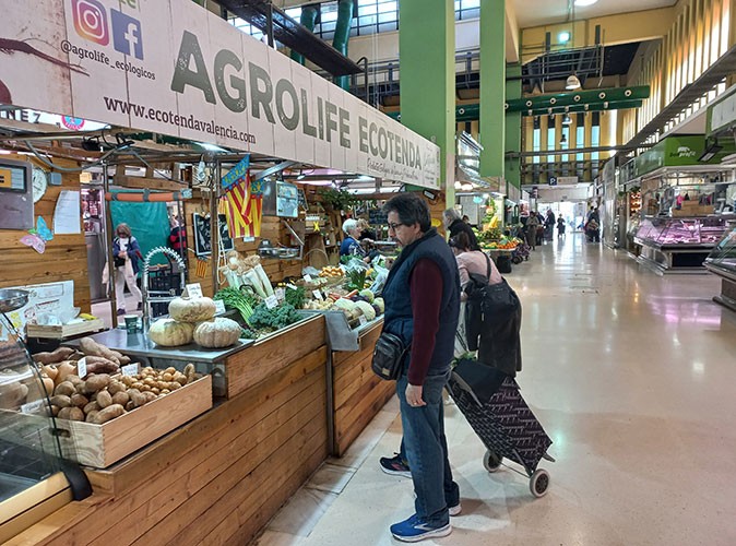 An eco-friendly market stall to visit in Valencia A fruit and vegetable stand with several people inside a market hall
