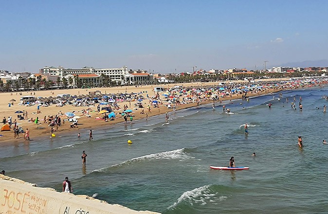 one of many sustainable activities in Valencia: spend a day at the beach A golden sandy beach with a lot of people and a blue sky