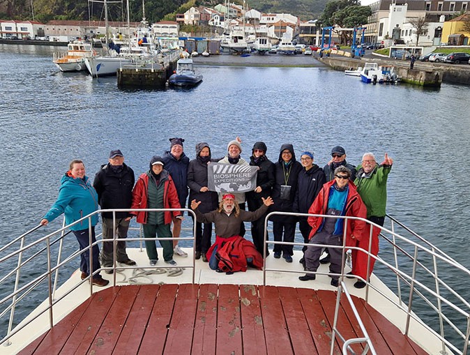 A group of people posing for a photograph on a boat with a marina in the background