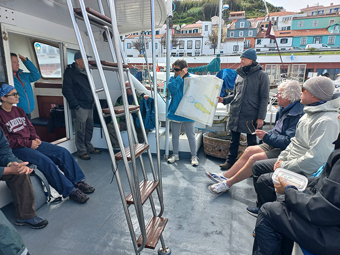 2 women holding a map on a boat speaking to other people sitting around them