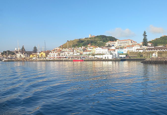 houses and boats as seen from the water with a green hill in the background