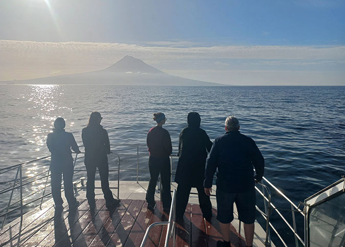 5 people on the bow of a boat looking out at sea