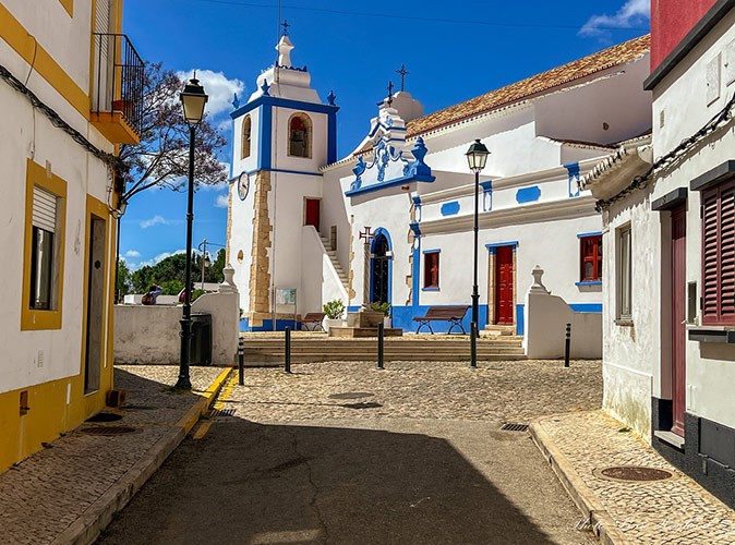 An empty street leading to a blue and white church
