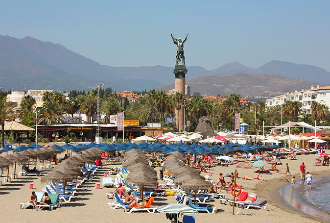 A beach perfect for a family day in Marbella A sandy beach filled with sun loungers, umbrellas and several people