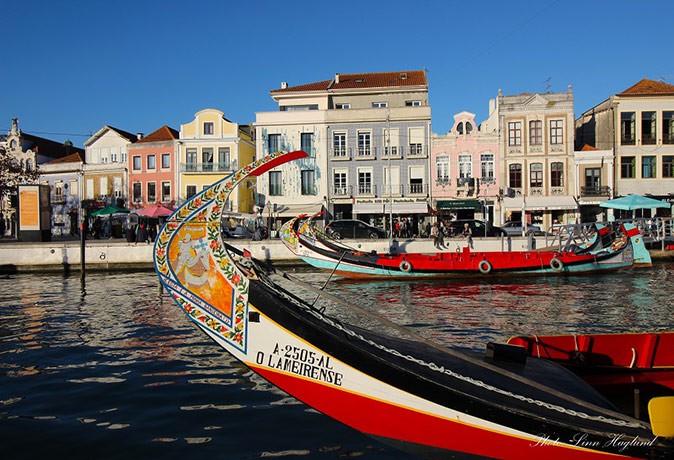 Traditional Portuguese boats on a canal with a colorful row of houses in the background