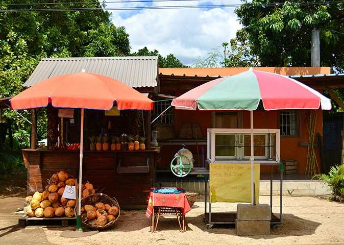 A food stand in Mauritius 2 umbrellas in front of a food stand with fruit on display