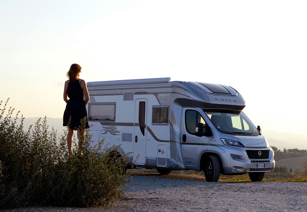 A woman in a dress standing in front of a large RV