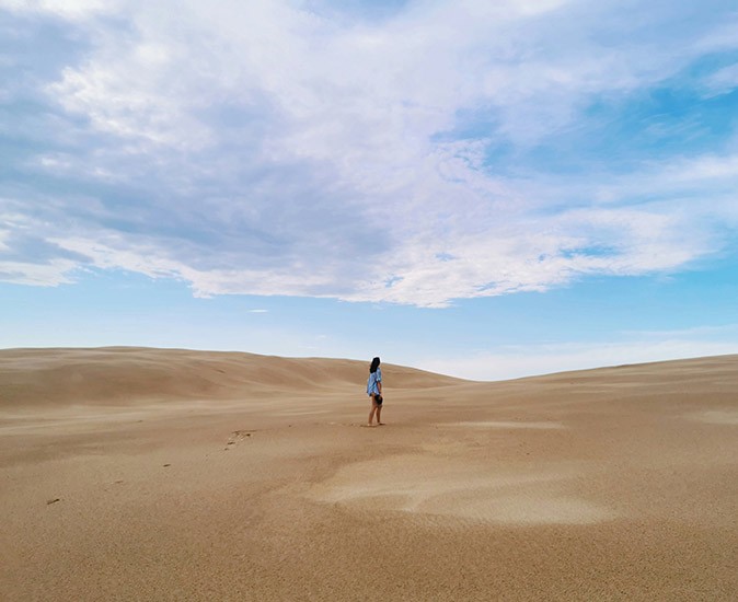 Things to know before moving to Australia: the country is huge! a woman walking in sand dunes with nothing else in sight