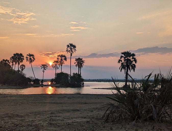 Liwonde National Park, Malawi sunset over a national park in Malawi with a lake, palm trees and sandy grounds
