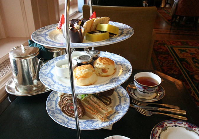 A table with a tea cup and a tray of pastries