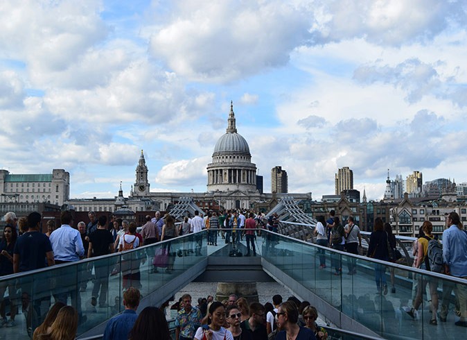 A crowd of people walking across two bridges in London