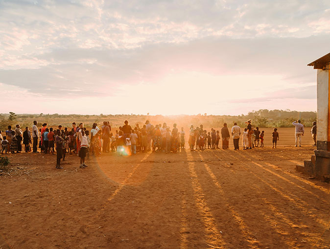 What it's like to live in Malawi A row of a people standing in red sand, admiring a beautiful sunset