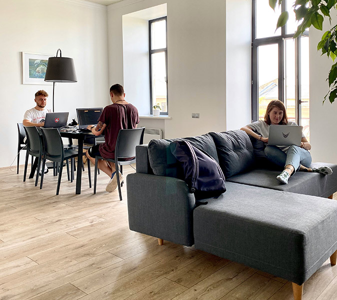 choose the right coliving in Spain 2 guys working on their laptops at a table and a woman on a large couch working on her laptop
