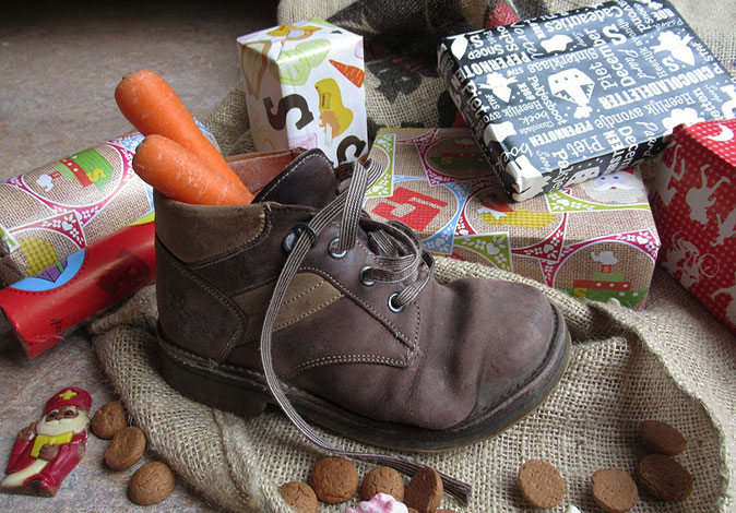 Enjoying Christmas traditions around the world A shoe with 2 carrots sticking out of it, surrounded by wrapped gifts and some candy