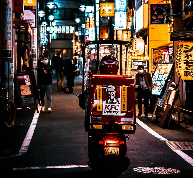 A Christmas tradition in Japan A scooter with a KFC delivery box on the back, surrounded by Japanese shop signs