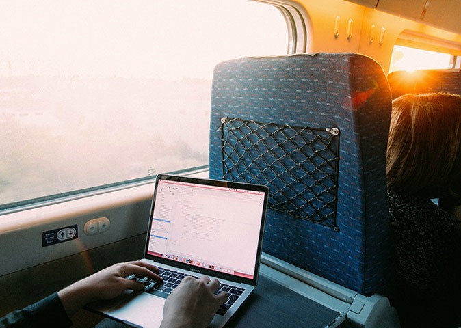 Downsides of Portugal as a digital nomad destination hands on a laptop inside a train next to a window