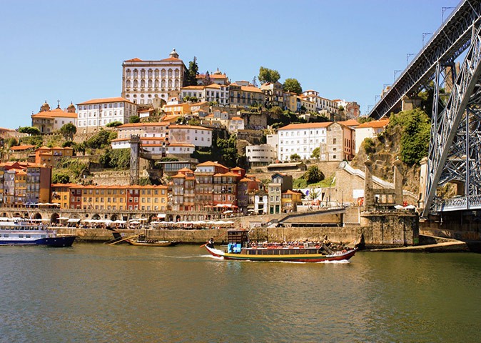 Porto, one of the digital nomad locations in Portugal A Portuguese town built on the edge of a river with boats and part of a bridge