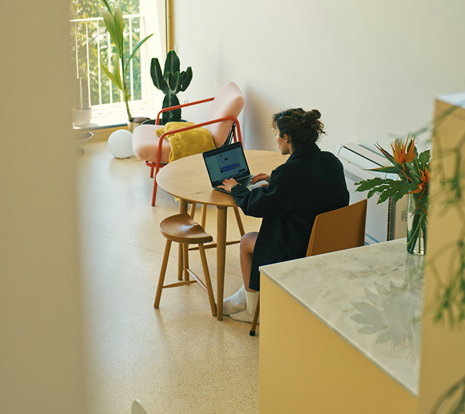 Working remotely from Portugal A woman working on her laptop at a round table in a bright, almost empty room