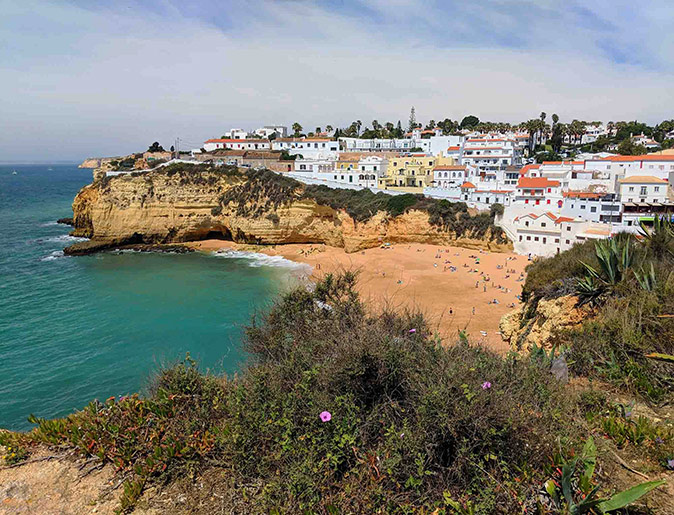 The Algarve, a popular Portuguese digital nomad destination A coastline with a sandy beach, cliffs on both sides and lots of white houses in the background
