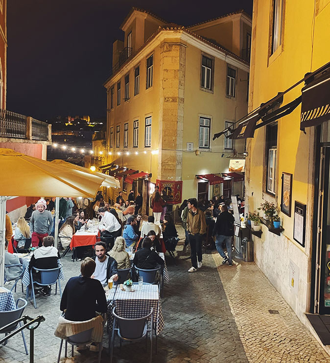 One of the best neighborhoods in Lisbon to live A terrace with a lot of people inside a city in the evening