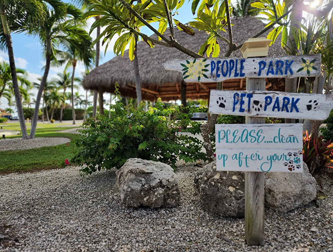 One of the best campgrounds in South Florida Wooden signs pointing to 'People Park' and 'Pet Park' with a cabana and several palm trees in the background