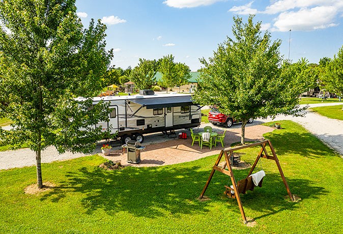 Camping in Florida in winter A large RV parked at an RV park surrounded by trees, a seating area and a bbq