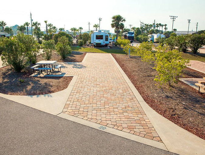One of the best RV parks in Florida An empty RV site on a campground with a picnic table, several trees and an RV in the background