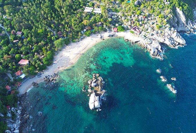 Beaches in Koh Tao vs Koh Samui Aerial view of a white sandy beach with bright blue water and lush greenery