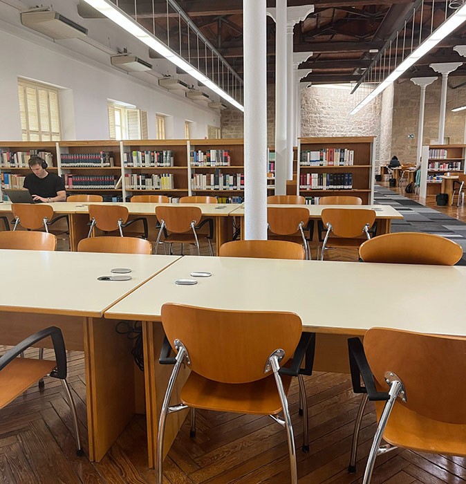 Working remotely on the Camino Frances A library filled with long white tables with brown chairs and one man working on his laptop