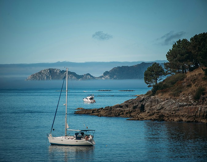 Yacht charter tips for Spain A motorboat and a sailboat anchored around a rocky coastline